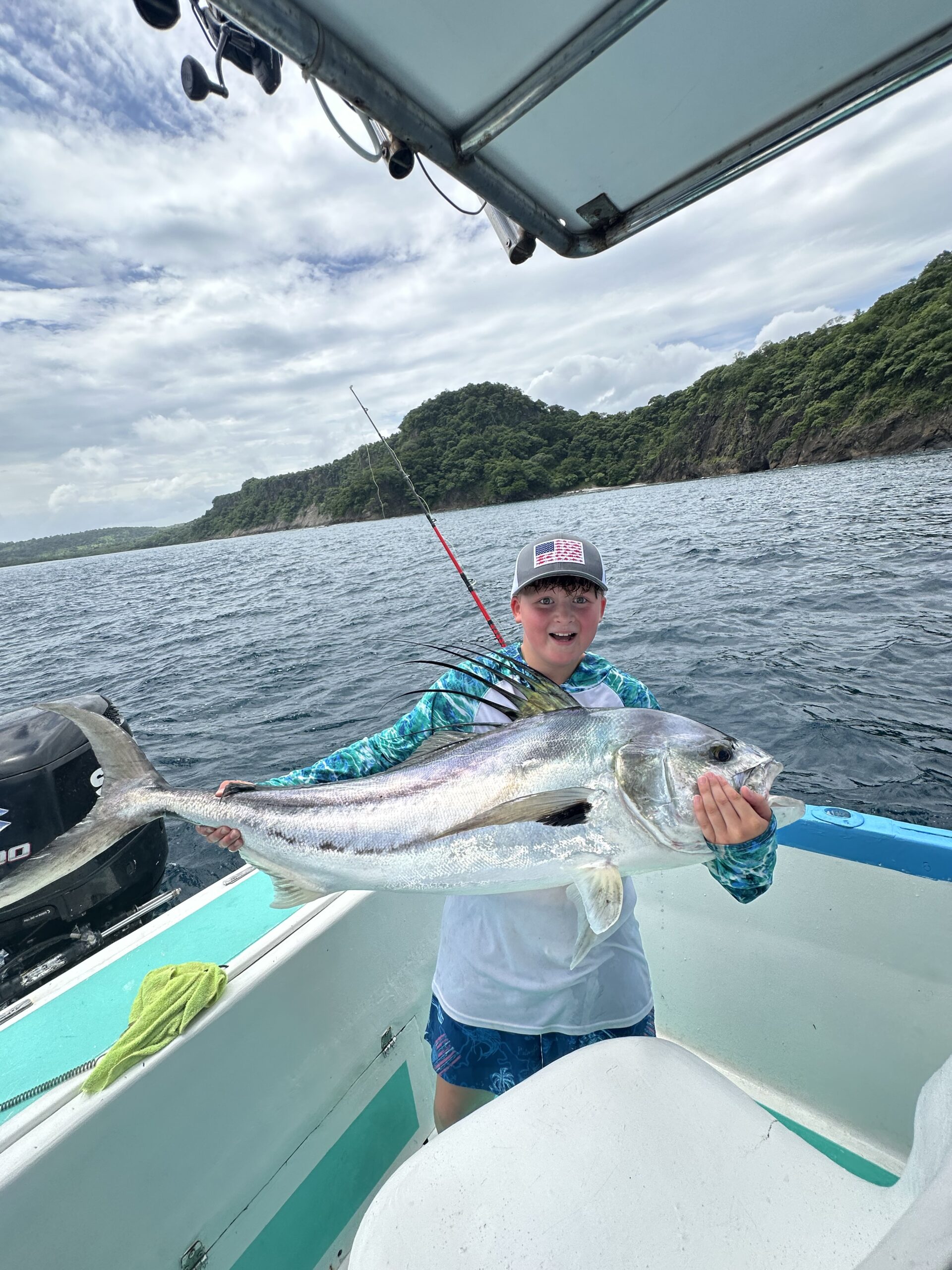 Happy child holding a rooster fish during sport fishing tour